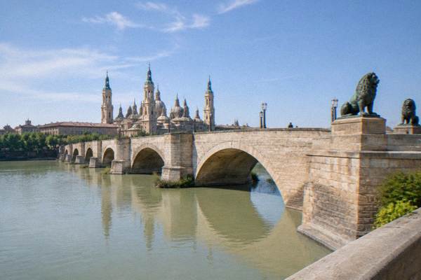A small guided group stopping in front of the Basilica del Pilar while a guide explains the facade.