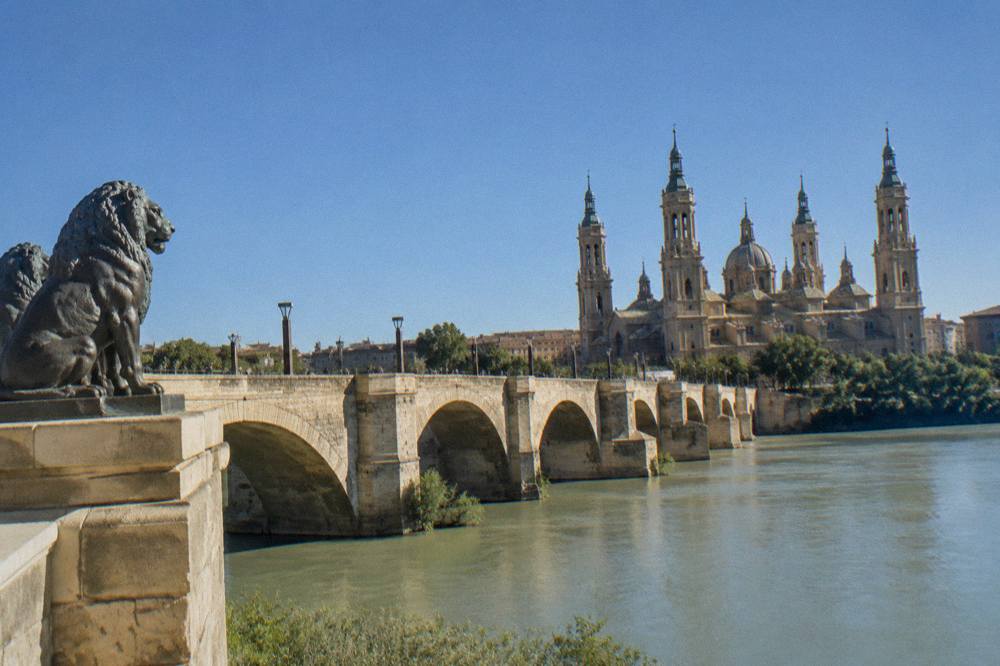 The Ebro river flowing under the Puente de Piedra stone bridge in late afternoon light
