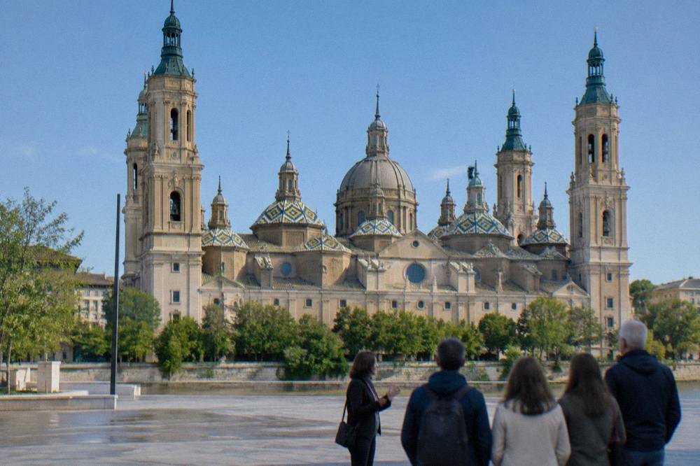 A guide speaking to a small group of visitors beside the Basílica del Pilar in Zaragoza