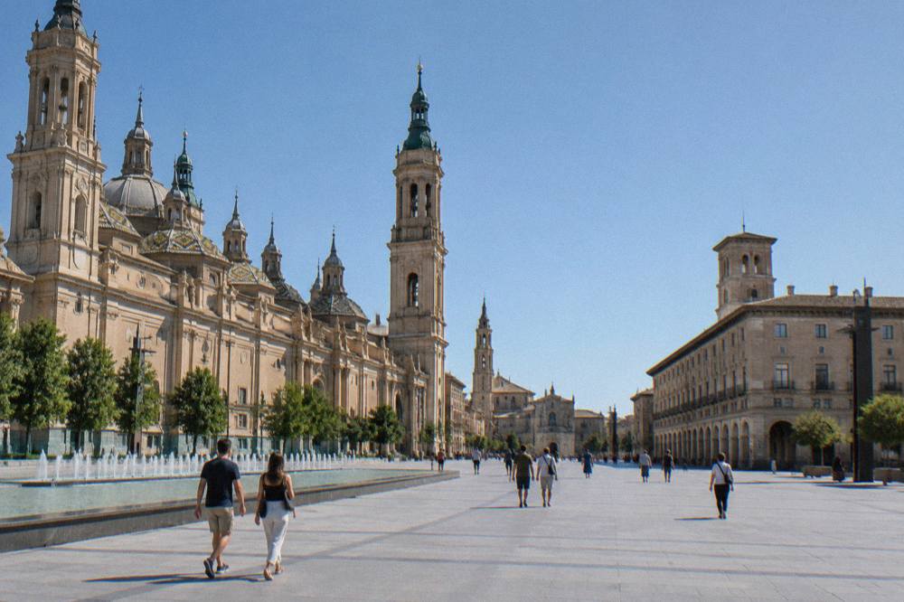 Visitors walking across Plaza del Pilar between the basilica and La Seo cathedral in Zaragoza