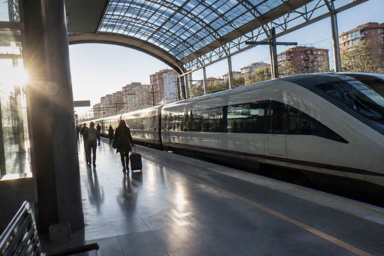 A high speed train standing at a station platform under a curved glass roof
