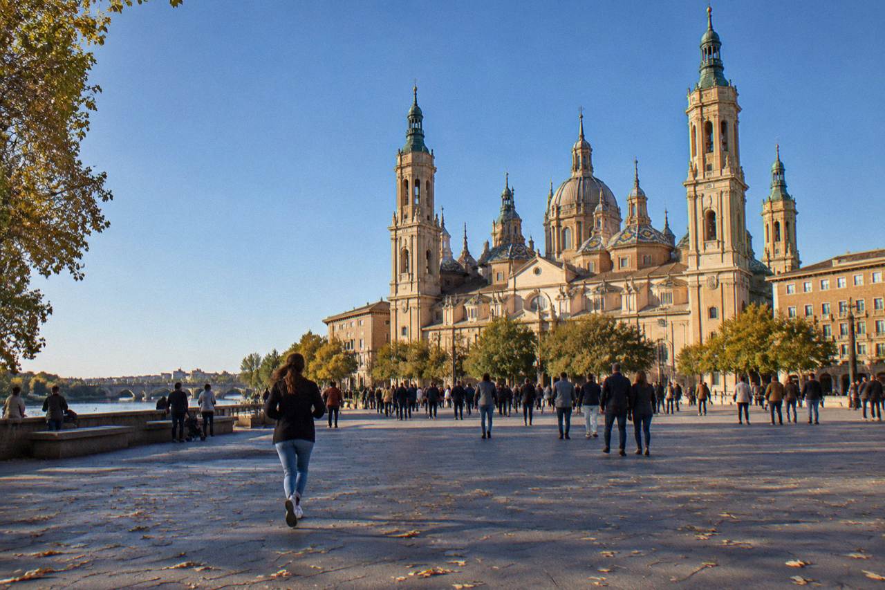 Crowds filling a wide square in Zaragoza in front of the domed Basilica del Pilar on a bright October day