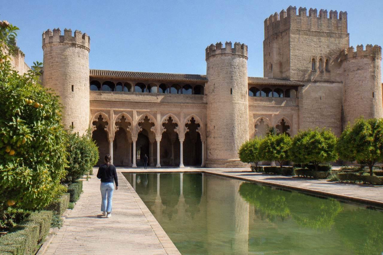 The ornate arched facade and tower of the Aljafería Palace in Zaragoza under a clear sky