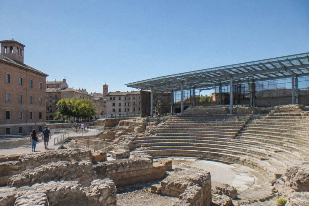 Visitors walking among the stone foundations of the Roman theatre museum in Zaragoza