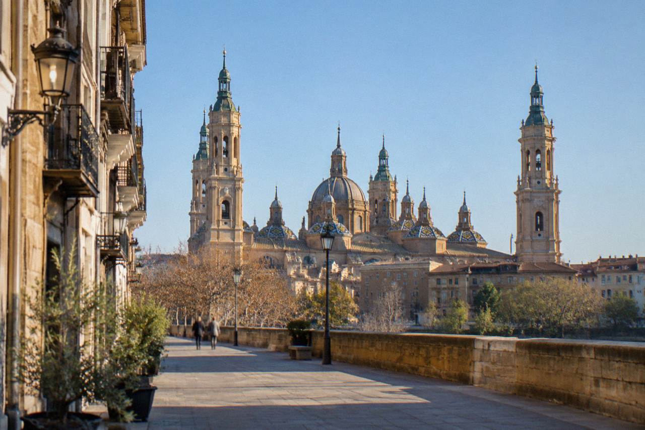 A quiet stone street in Zaragoza's old town with the Basilica del Pilar rising above the rooftops
