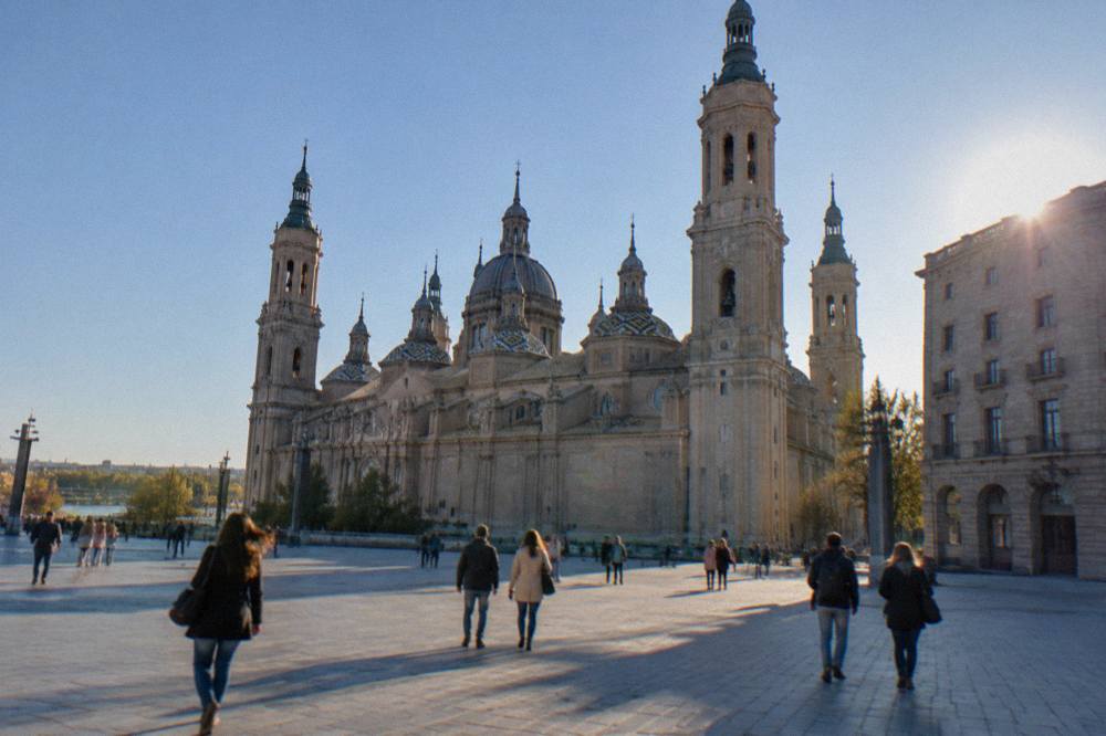 Visitors walking across Plaza del Pilar between the Basilica del Pilar and La Seo in Zaragoza