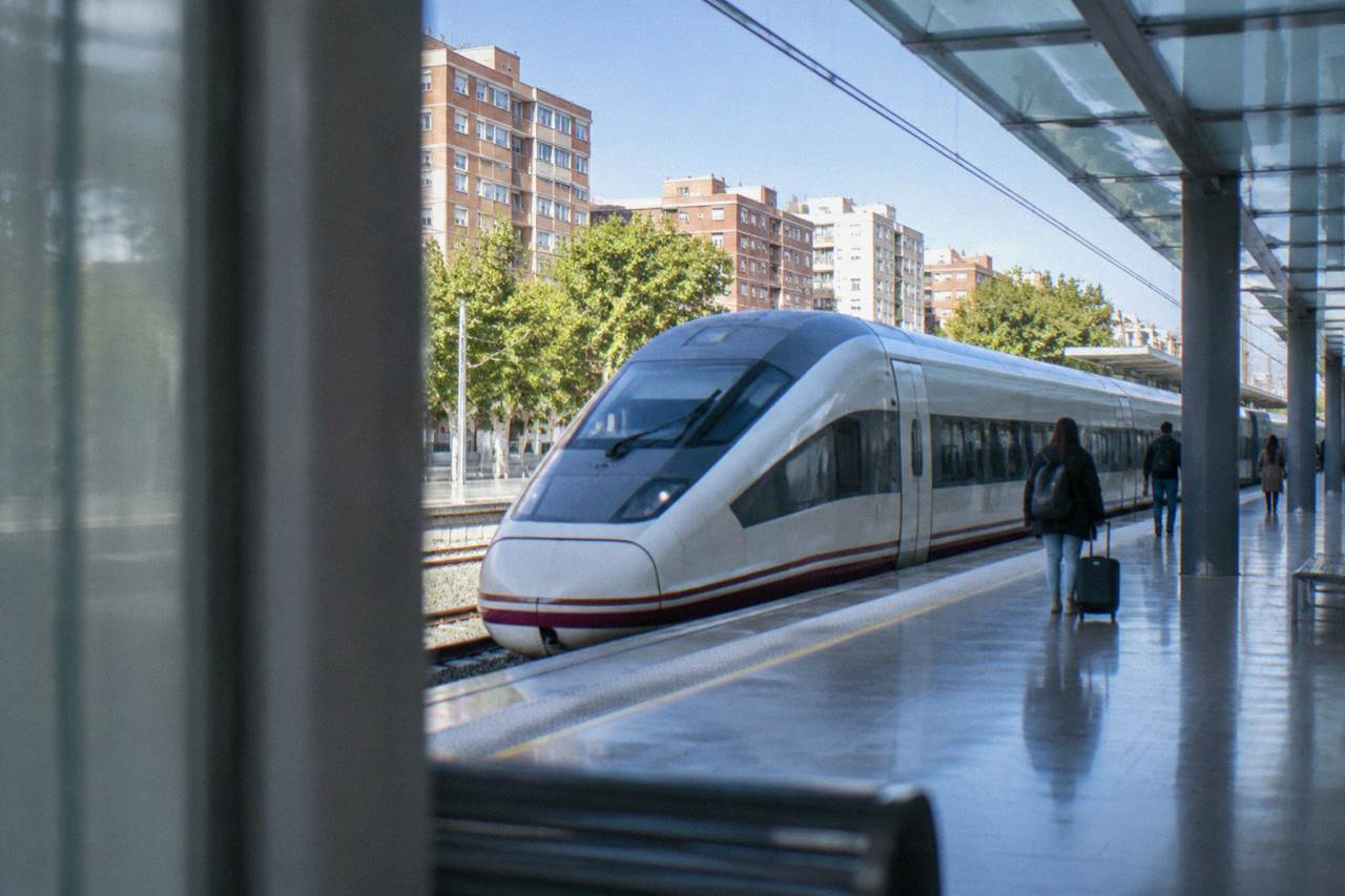 High-speed train standing at a modern railway station platform under a glass canopy