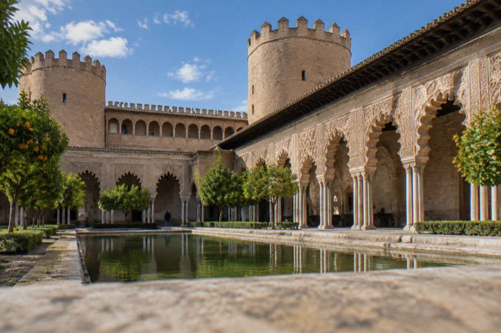 The ornate arches and carved stucco of the Aljafería palace courtyard in Zaragoza