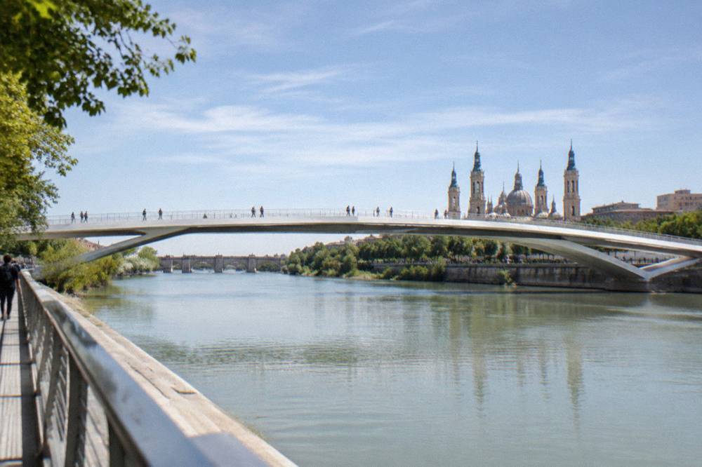 Modern white bridge structure spanning the Ebro river with people crossing on foot