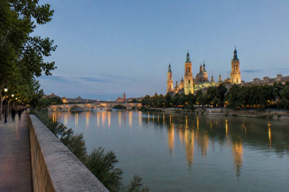 Evening view of illuminated bridges and towers reflected in the Ebro river