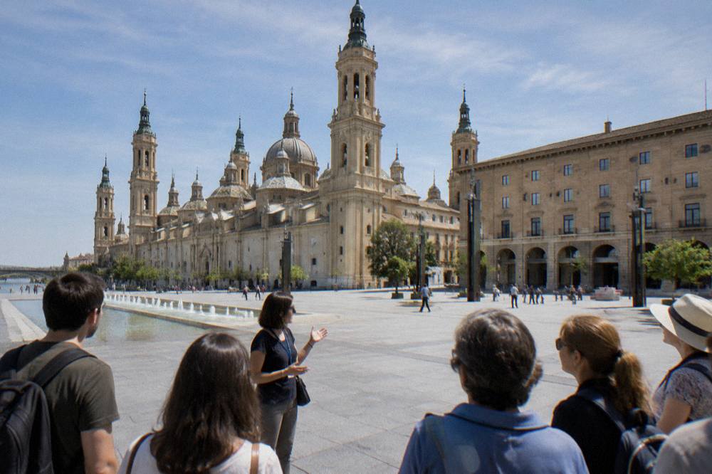 A tour guide speaking to a small group on a stone square in Zaragoza's old town