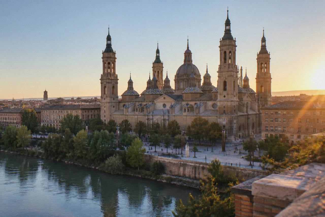 The towers of the Basilica del Pilar rising above the rooftops of Zaragoza's old town at golden hour