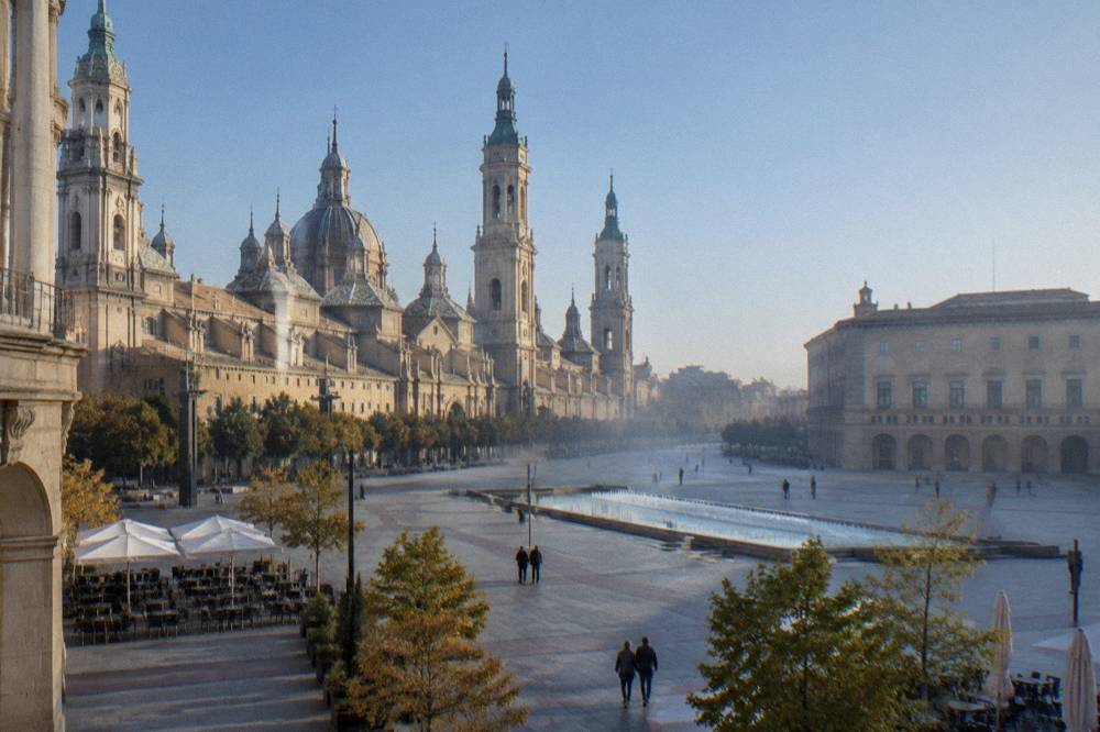A plaza in Zaragoza's old town with outdoor tables and historic arcaded buildings in daylight