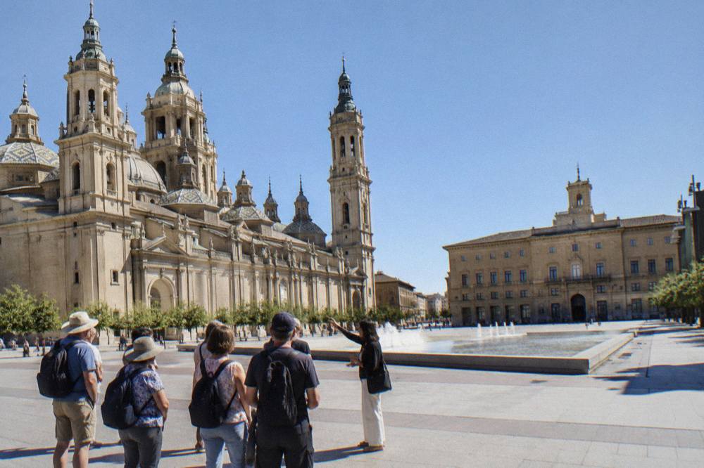 A guided tour group gathered in a sunlit square in Zaragoza's historic centre