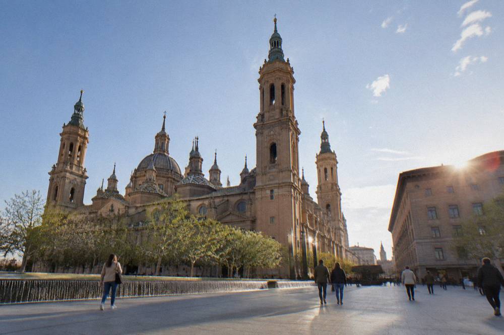 Spring sunlight on the brick facade of a church in Zaragoza with people walking past