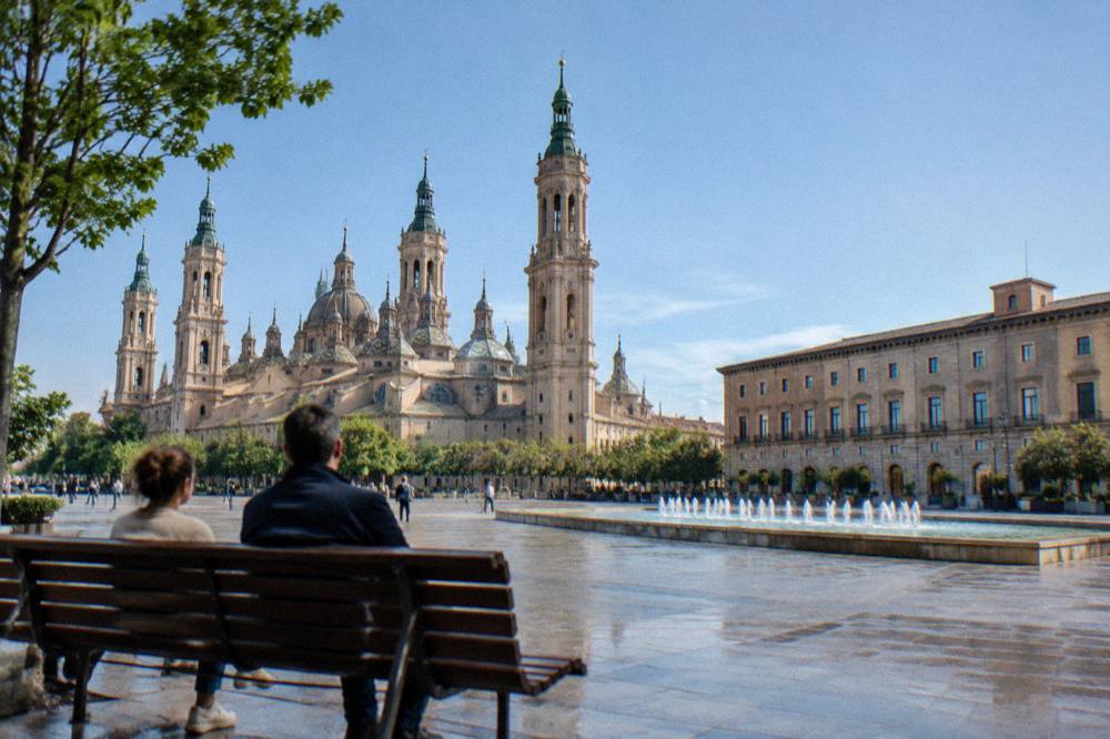 People sitting on a bench in a small neighbourhood square in Zaragoza