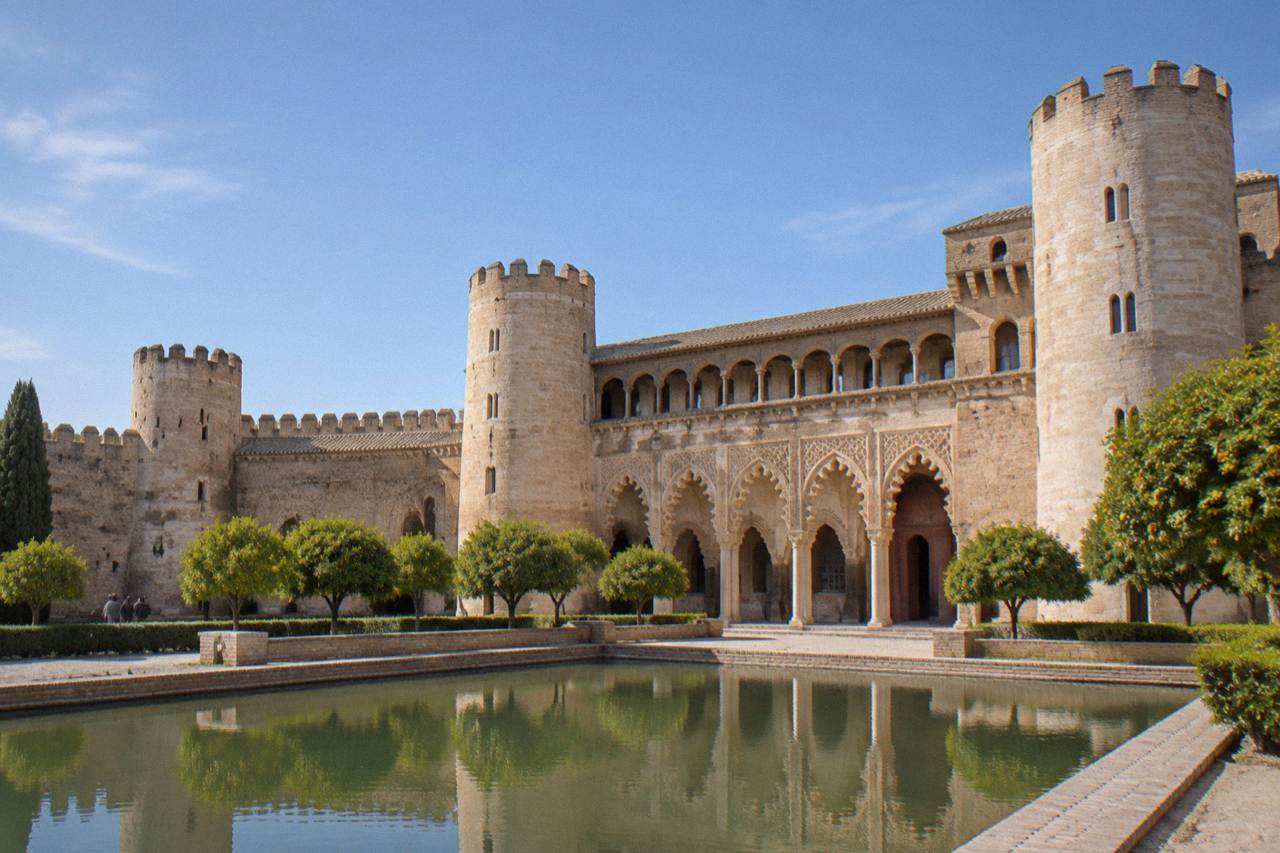 The ornate arched facade and tower of the Aljaferia Palace in Zaragoza under a clear sky