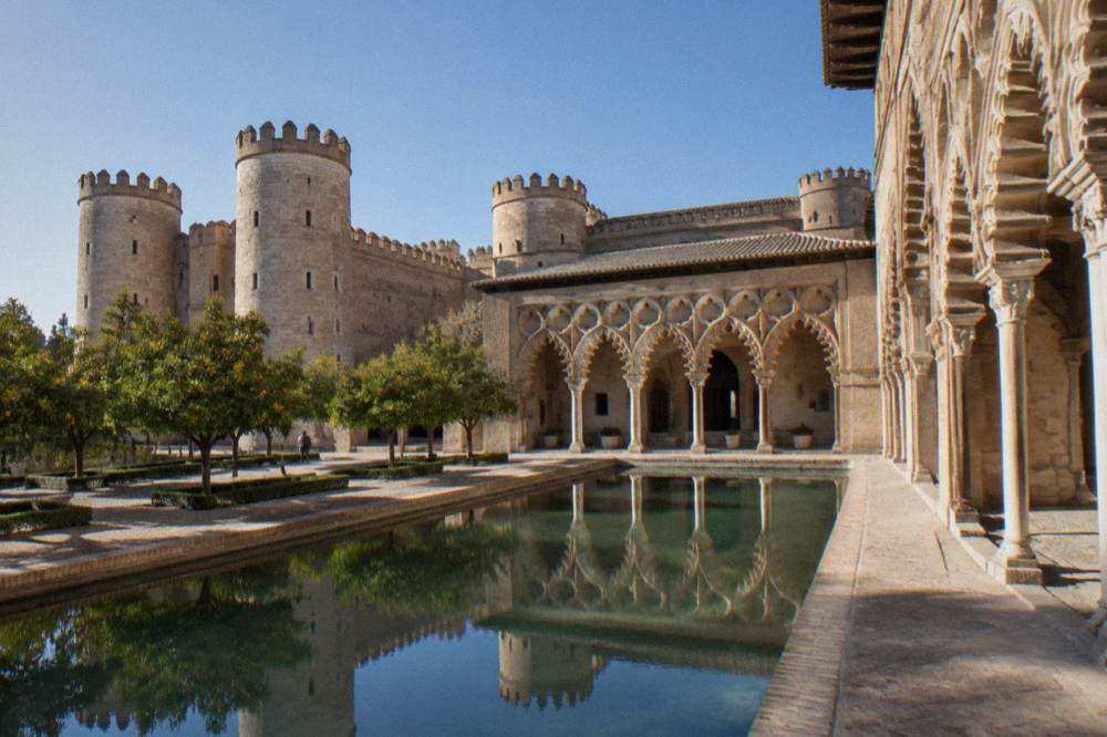 The restored Islamic courtyard of the Aljaferia Palace with its arcades reflected in the water channel