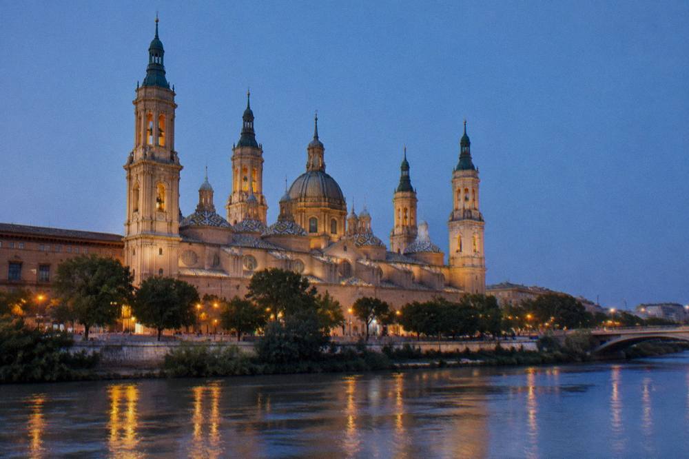 The facade of the Basílica del Pilar seen from across the Ebro at dusk