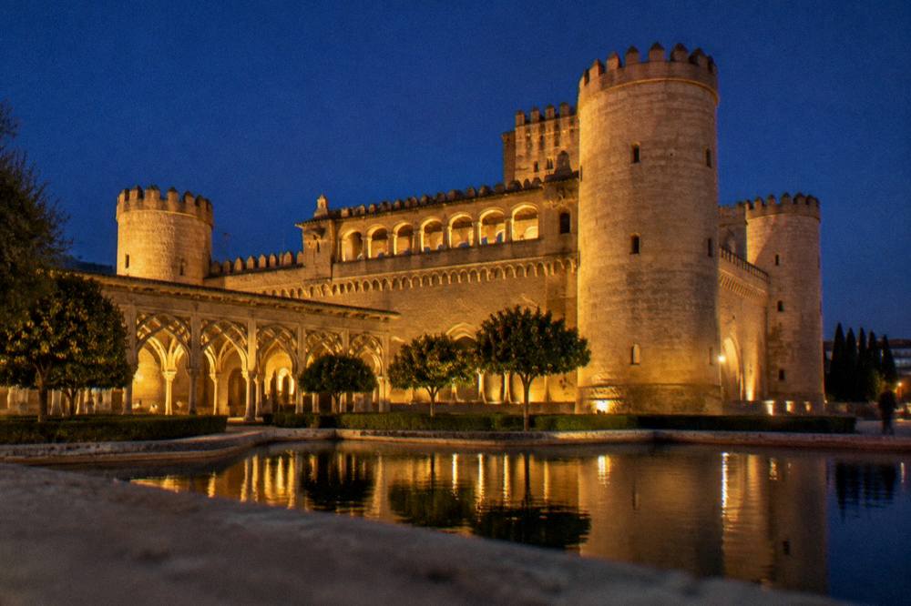 The illuminated Aljaferia Palace tower against an evening sky
