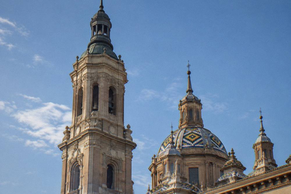 A close view of one of the Basilica del Pilar's towers with its tiled dome against a blue sky