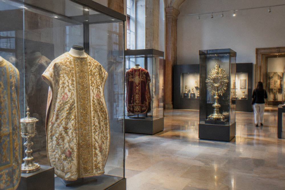 A museum gallery displaying religious vestments and historic objects inside the Basilica del Pilar complex