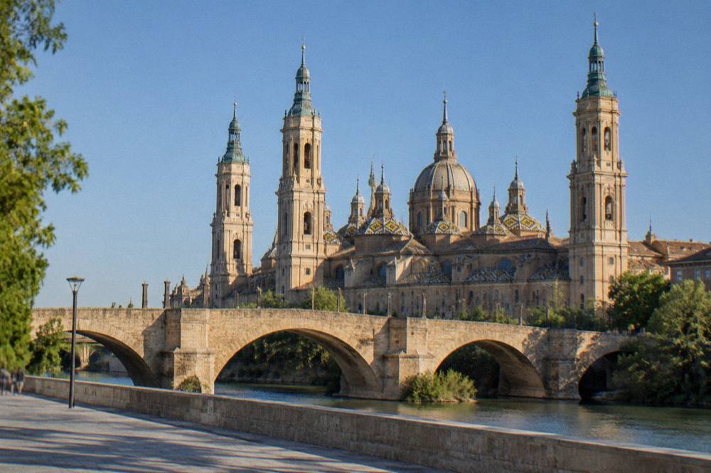 The stone bridge over the Ebro with the basilica towers rising behind it in the late afternoon