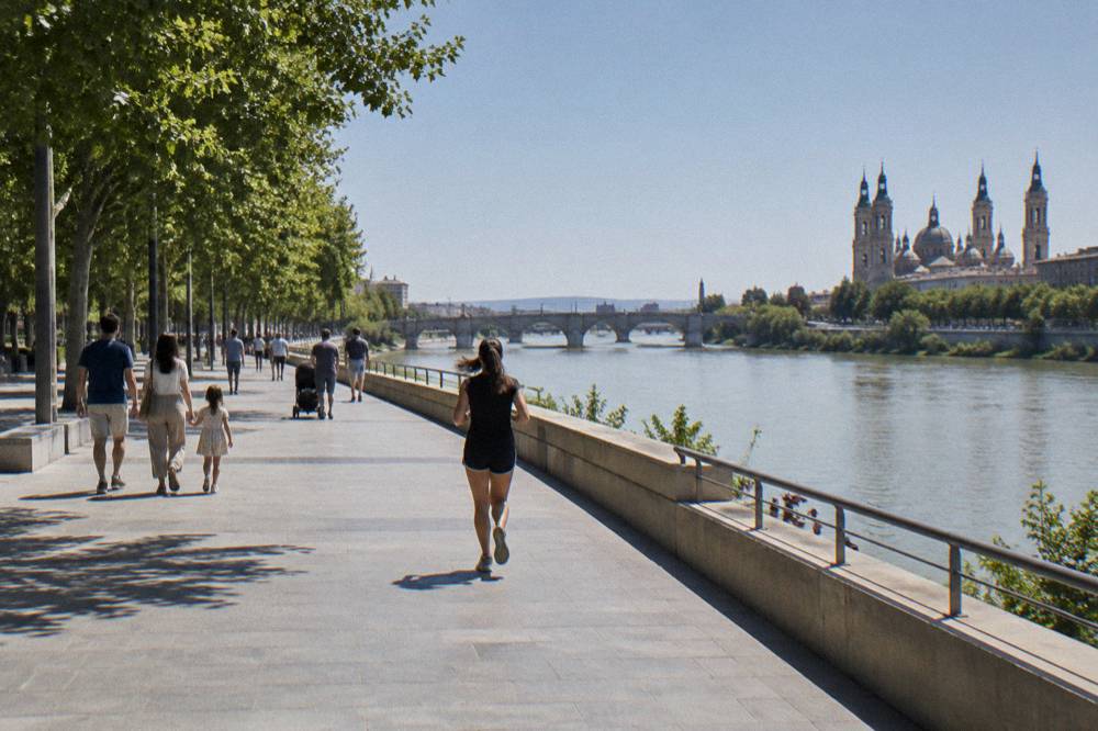 Families strolling on a wide riverside promenade beside the Ebro in daylight