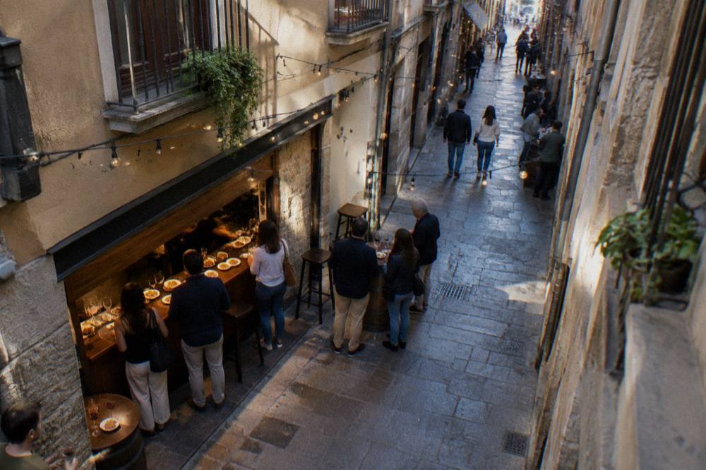People standing at a tapas bar counter with small plates and glasses of wine in Zaragoza