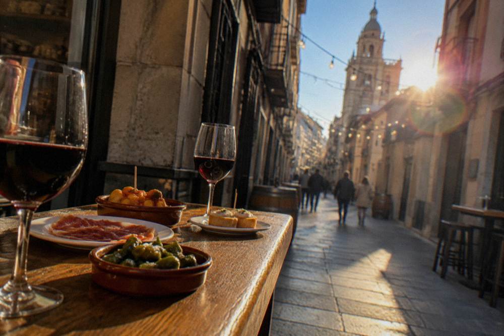 Small plates of Aragonese tapas and glasses of red wine on a wooden bar top