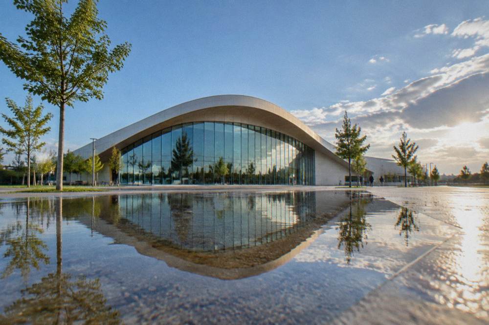 Glass facade of the river aquarium building reflected in a shallow water feature