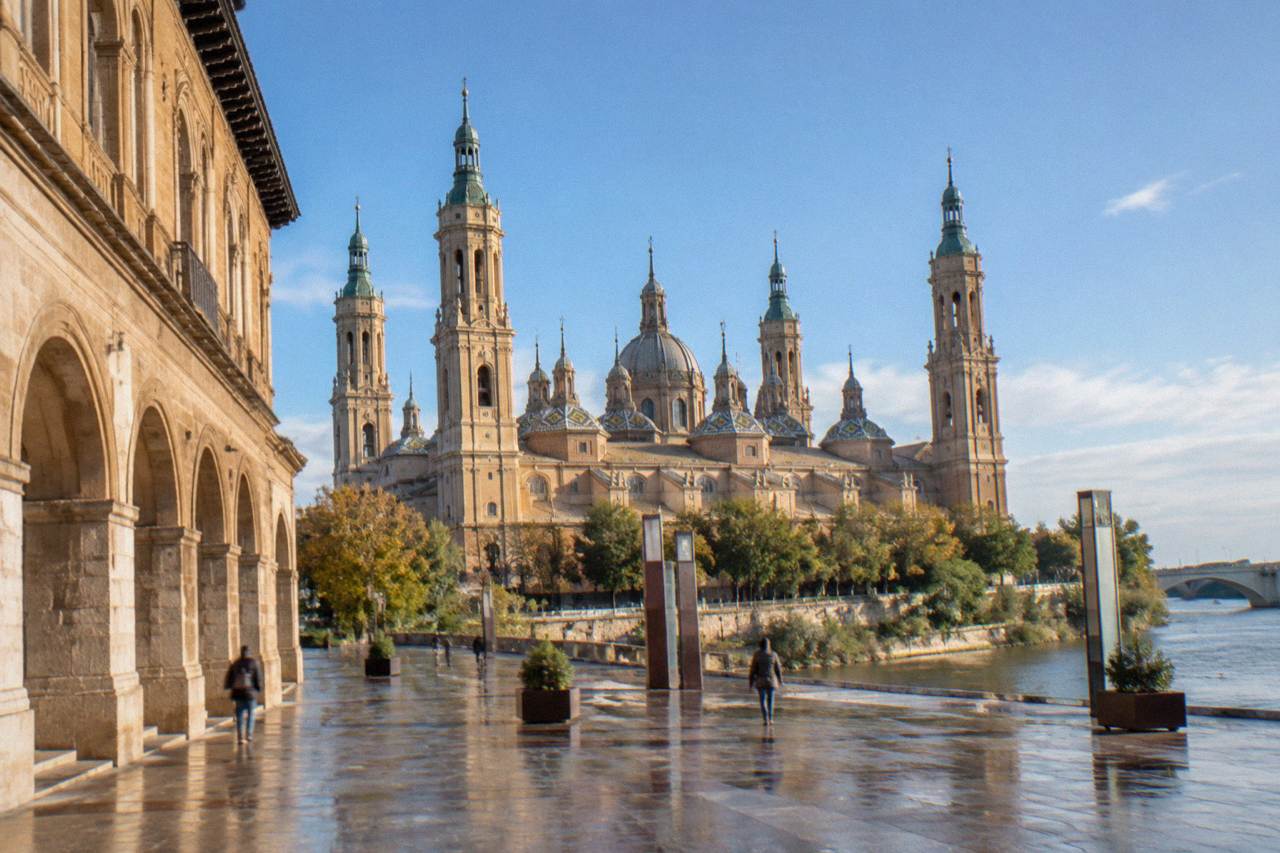 The arched stone facade of La Lonja with the towers of the Basílica del Pilar behind it