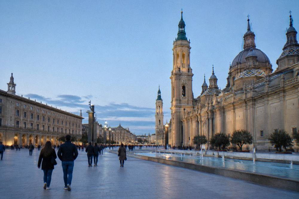 Plaza del Pilar in Zaragoza with pedestrians walking between La Lonja and the basilica