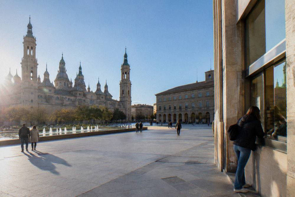 A ticket window in a Zaragoza museum with a visitor checking a notice board