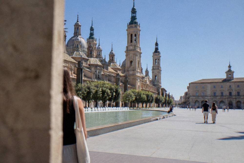 A wide exhibition square with grand pavilion buildings and palm trees in Zaragoza