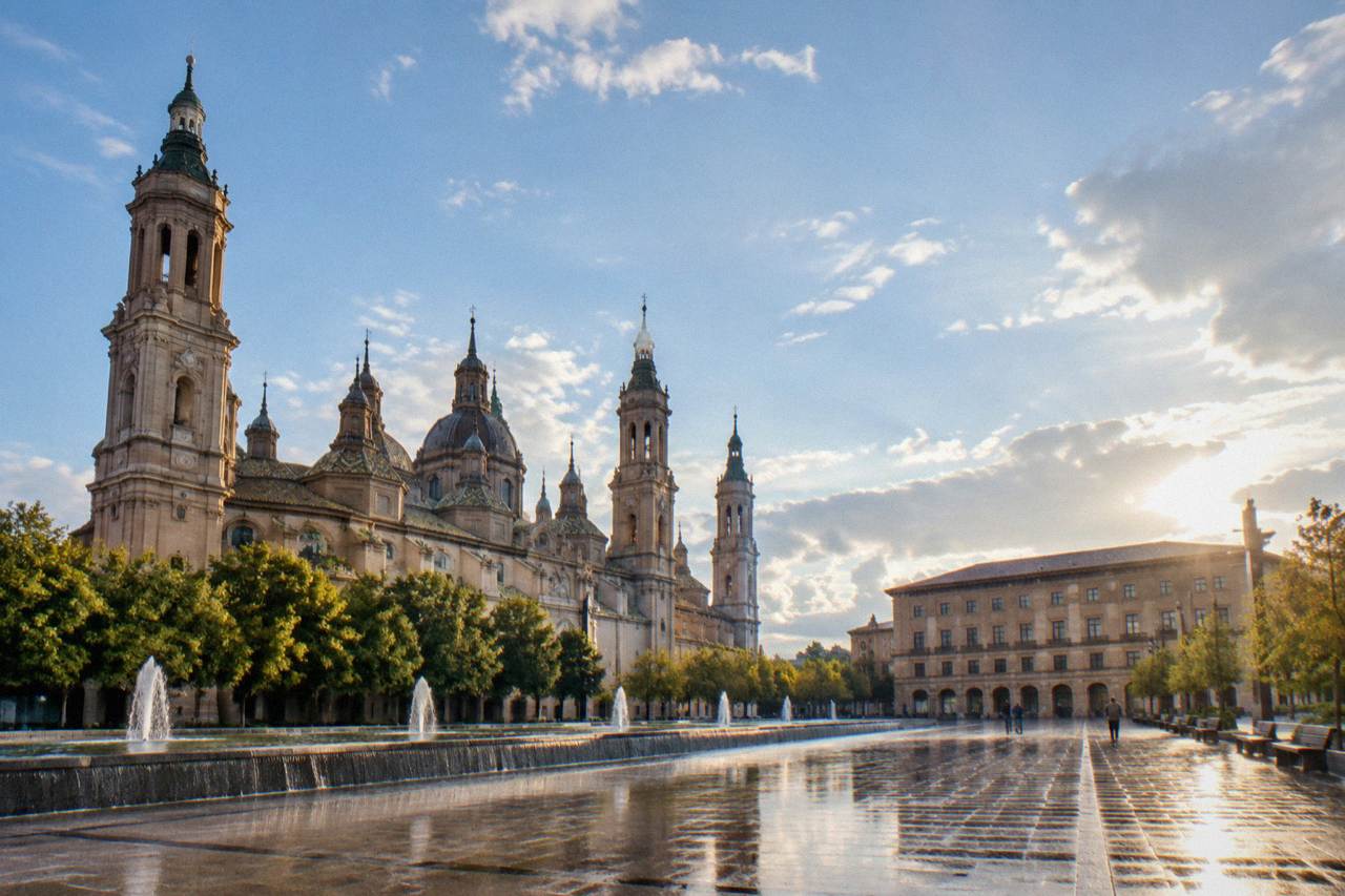 Tree-lined promenade in a large city park in Zaragoza with fountains and benches in the morning light