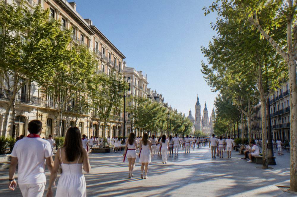 Crowds in white clothing filling a city boulevard during a festival offering