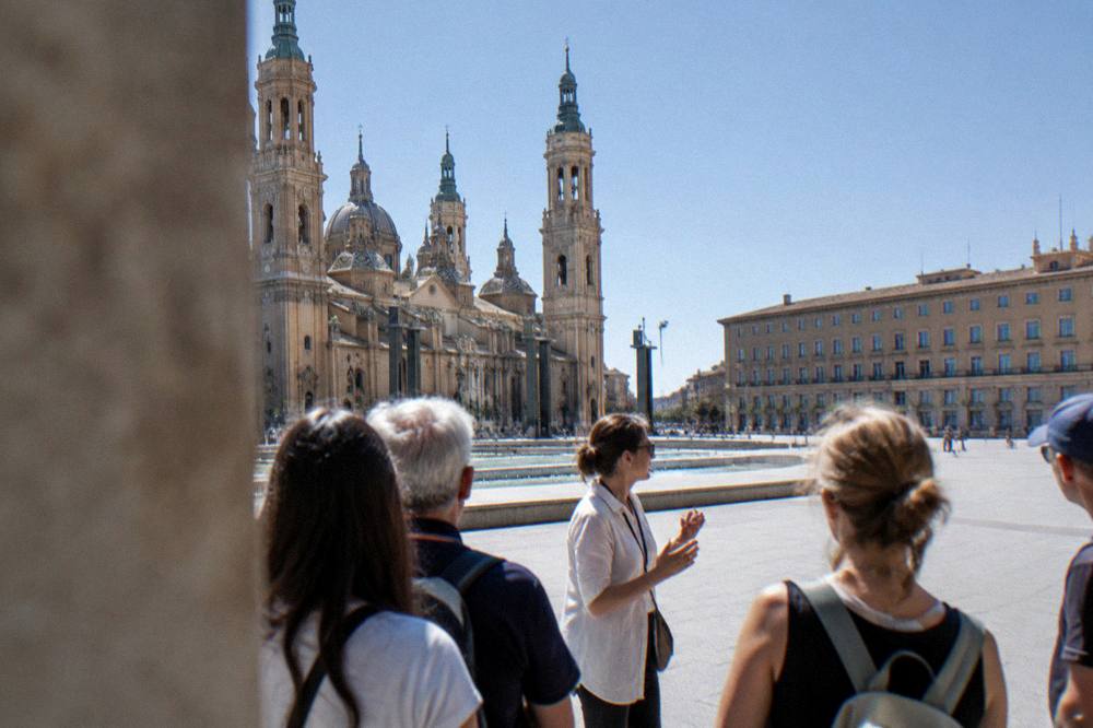 A tour guide speaking to a small group of visitors on a city street in Zaragoza