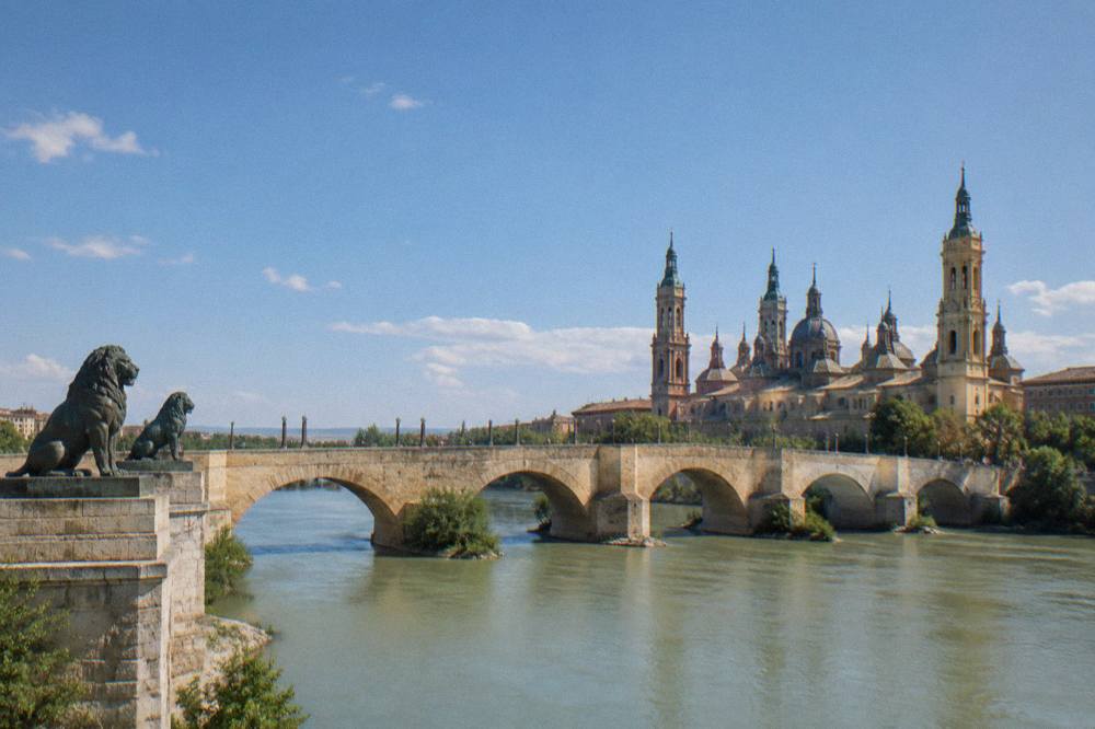 The Puente de Piedra stone bridge over the Ebro river with the basilica behind it