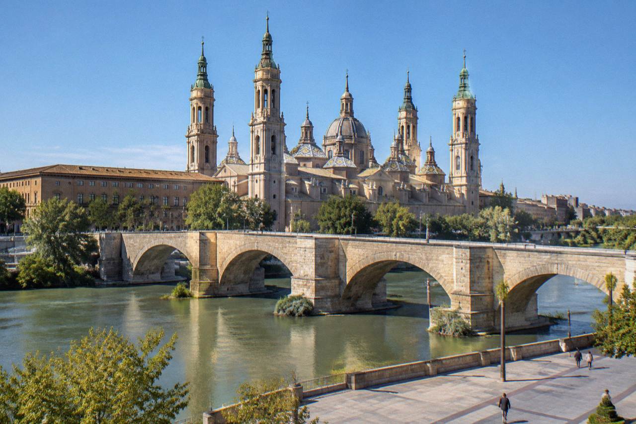 The stone Puente de Piedra bridge crossing the Ebro river with the Basilica del Pilar rising behind it