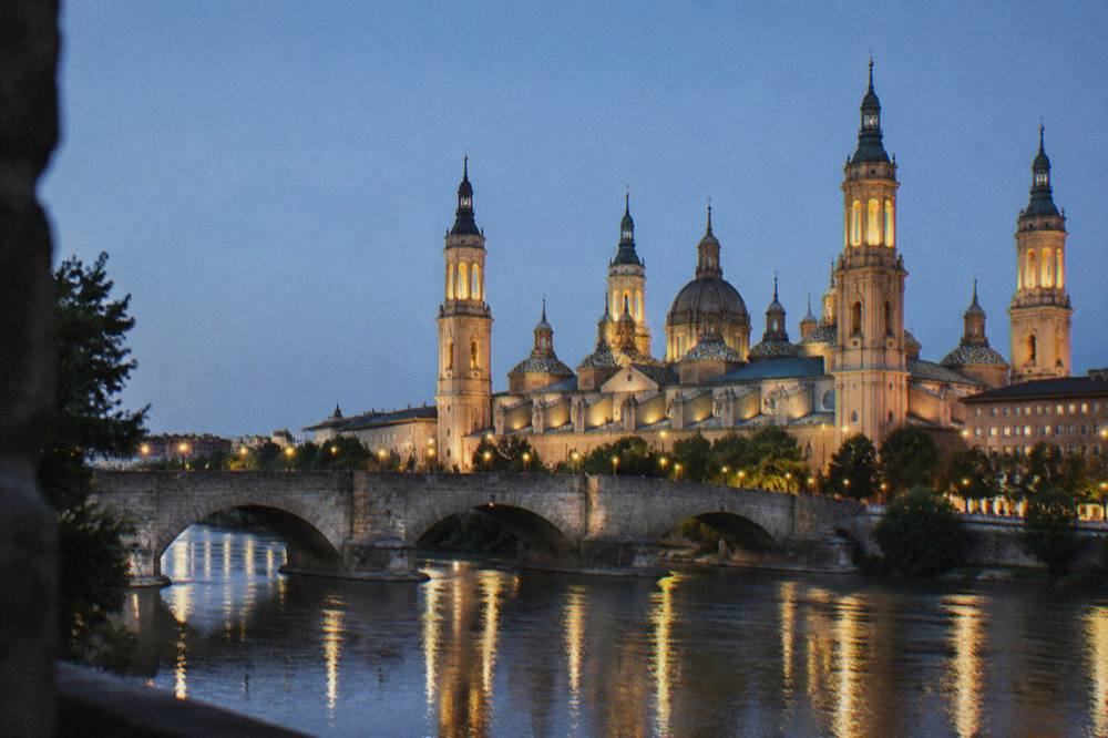 The stone bridge at night with the illuminated basilica towers behind it