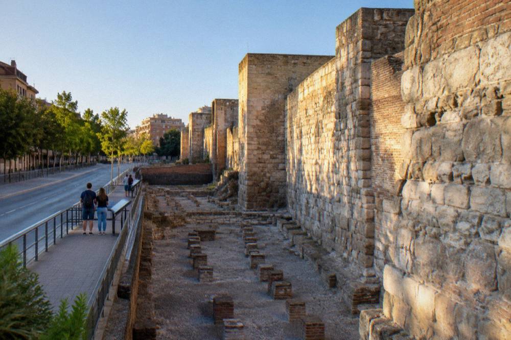 Visitors reading information panels beside the excavated Roman bath rooms in Zaragoza