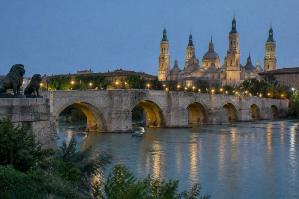 The Ebro riverside in Zaragoza with the stone arches of the Puente de Piedra in the evening light