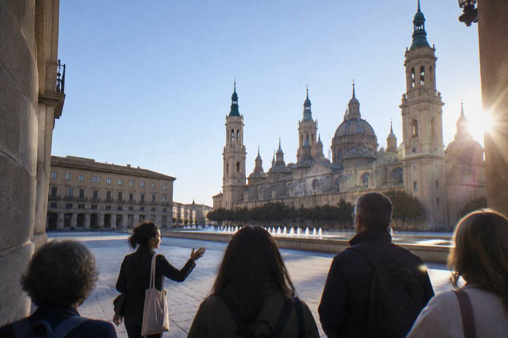 A local guide leading a small group of visitors through a narrow street of old Zaragoza