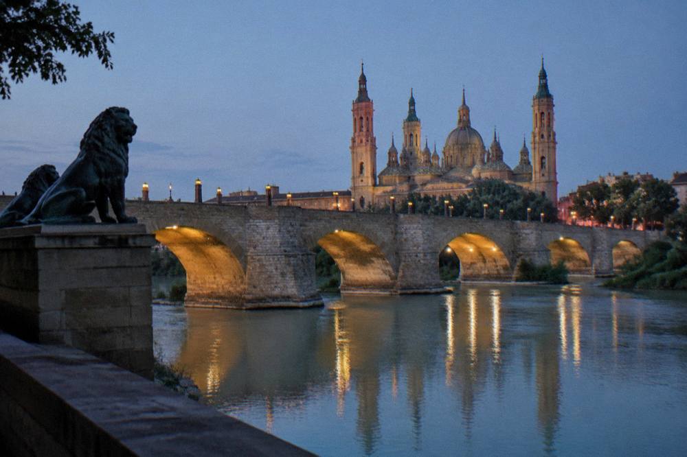 Evening light on a stone bridge arches reflected in a calm river