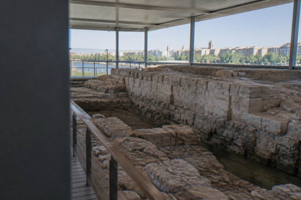 Ancient stone masonry of a Roman quay wall lit inside a modern museum gallery