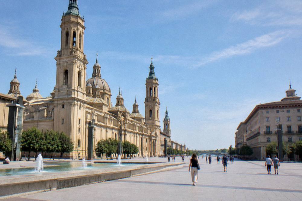 Narrow old town street in Zaragoza with stone buildings leading toward the Ebro river