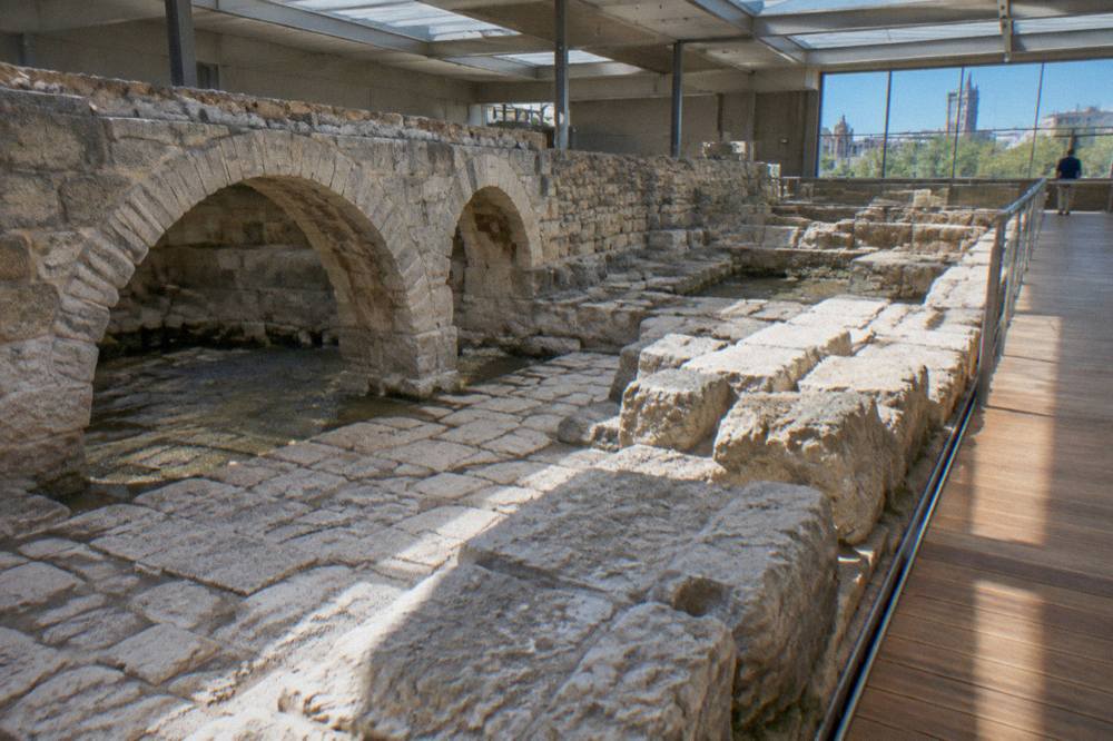 Stone arches and carved Roman masonry displayed in an underground museum hall