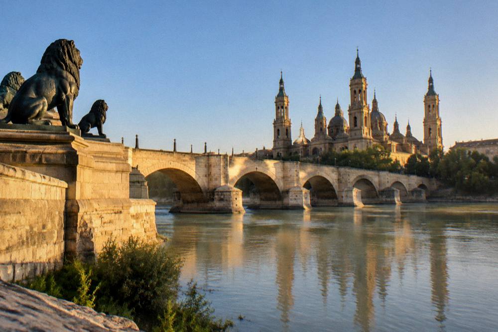 View of the Ebro river and Puente de Piedra bridge from the old town bank at golden hour