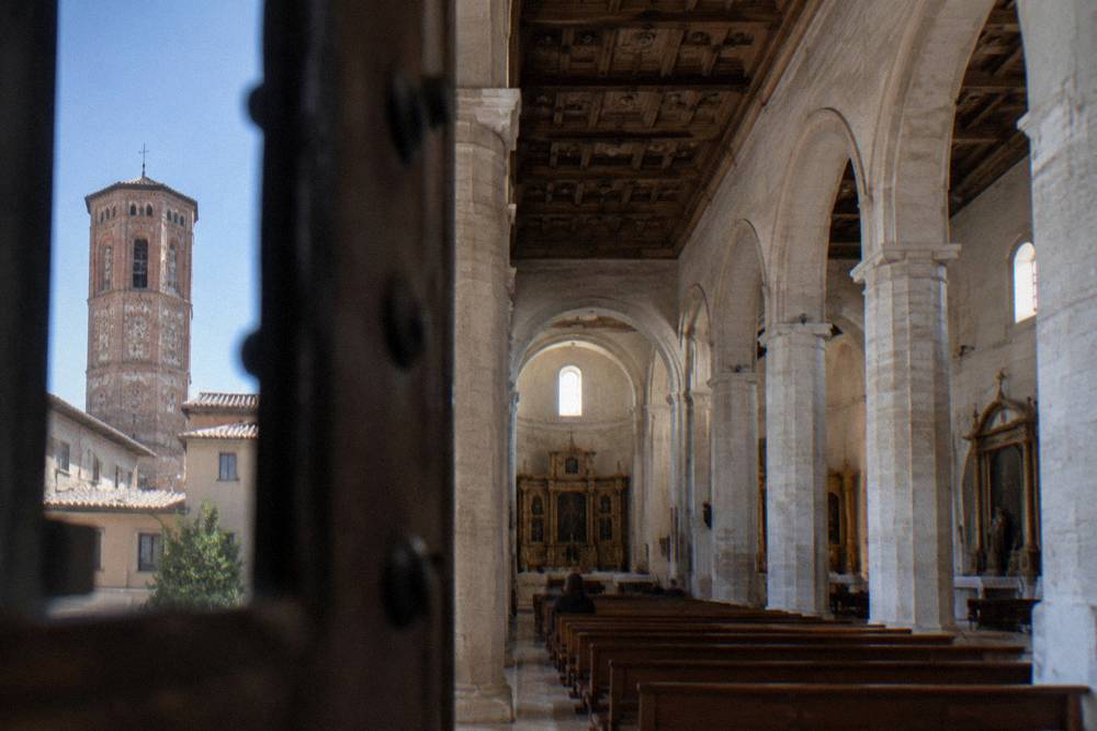 The interior of a single-nave church with pale stone columns, side chapels and a coffered ceiling